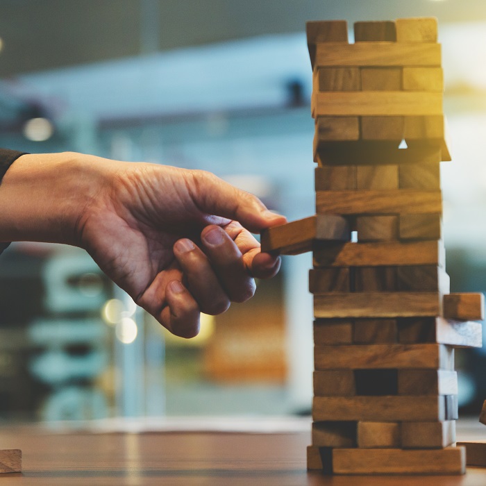 hand removing block from tower of blocks 