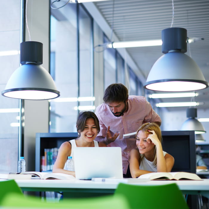 Three people at desk in work environment