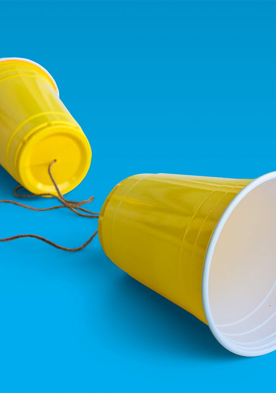 yellow plastic cups string between telephone talk blue background