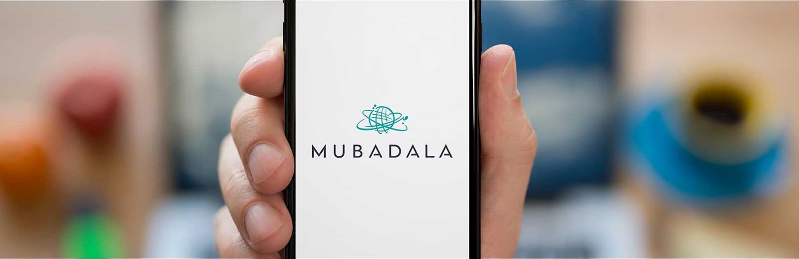 hand holding smart mobile cell phone cell app Mubadala white background