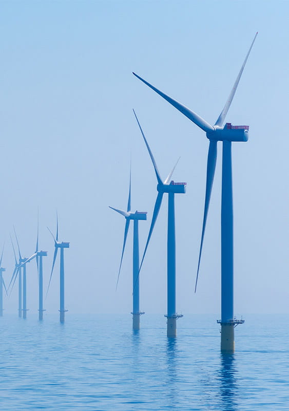 photo of a row of wind turbines standing in the blue sea water renewable energy