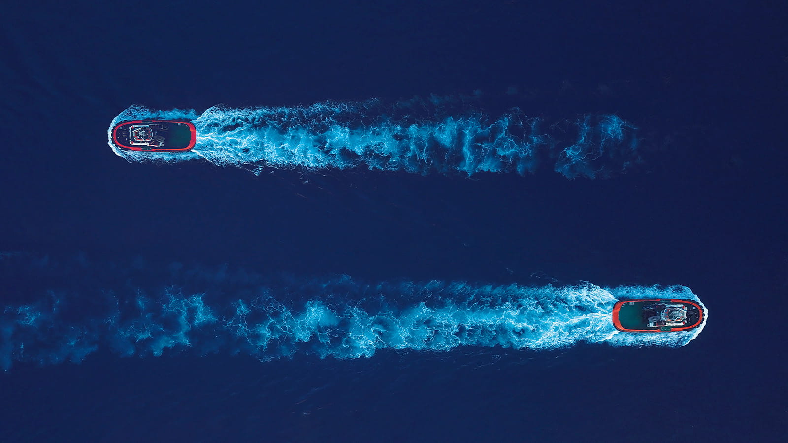 two boats birds eye aerial view passing each other going in different directions blue water