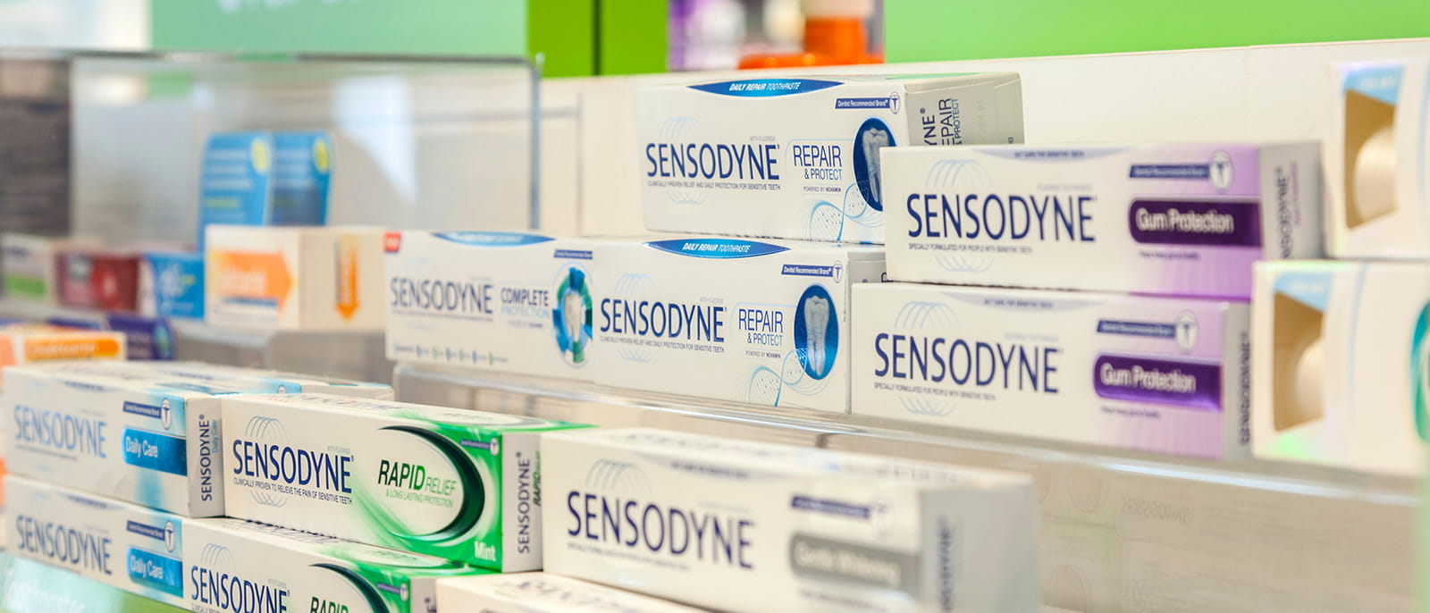 Store shelf of Sensodyne toothpaste boxes on display for sale pharmacy