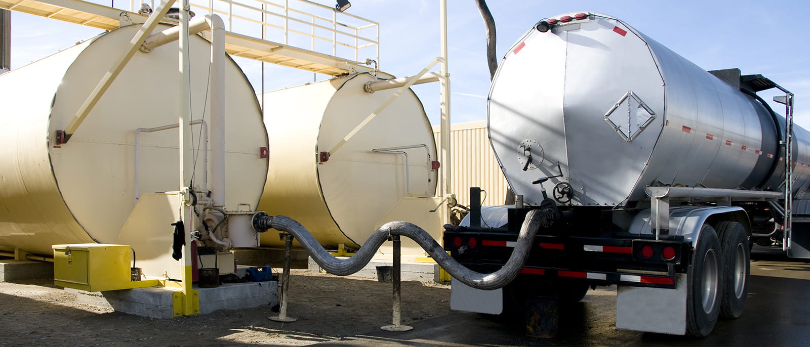 photo of an oil truck loading fuel hose from oil drum
