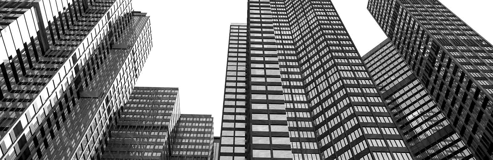 Skyscrapers and tall office buildings seen from below. Black and white image with monochrome style. White sky and neutral background.