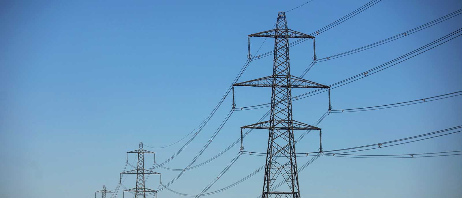 photo of power lines electric pylons against a blue sky