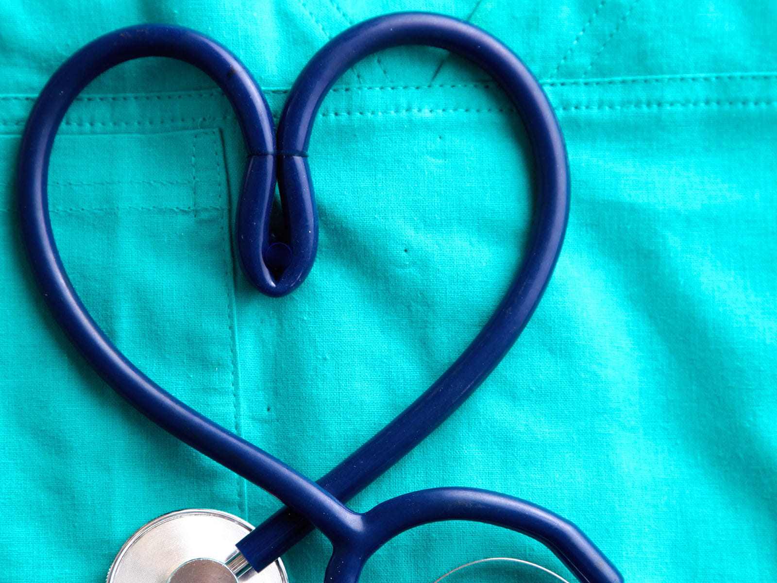 Stethoscope in the shape of a heart on a background of medical coat.