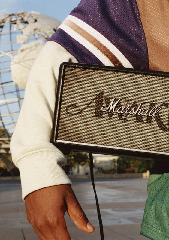 Marshall Awake speaker held under a boy's arm standing in front of the Unisphere globe, Queens, New York