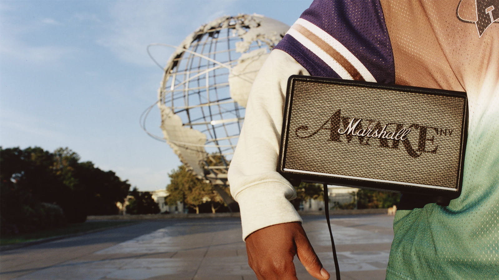 Marshall Awake speaker held under a boy's arm standing in front of the Unisphere globe, Queens, New York