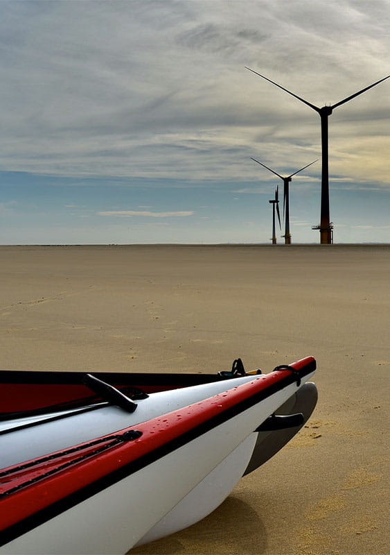 On Scroby Sands beach, near Great Yarmouth, Norfolk UK, kayaks wind turbines