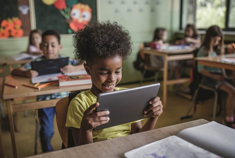 Happy girl e-learning on digital tablet in the classroom