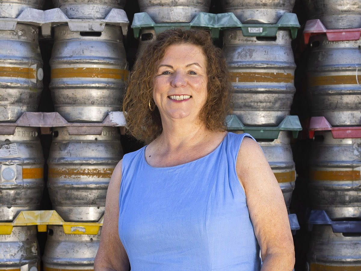 Karen Hester with a wall of kegs behind her