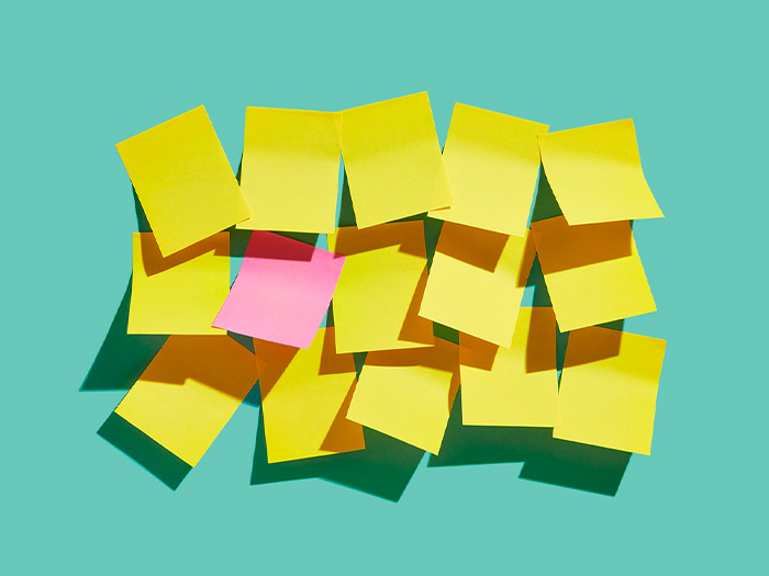 group of yellow sticky post it notes with one pink on a teal background