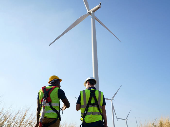 Wind turbines energy engineers walking inspect work at sites hard hats high-vis
