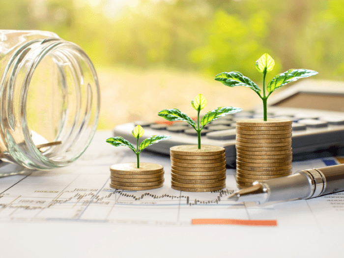 An empty jar, coins and plants on a pile of printed graphs