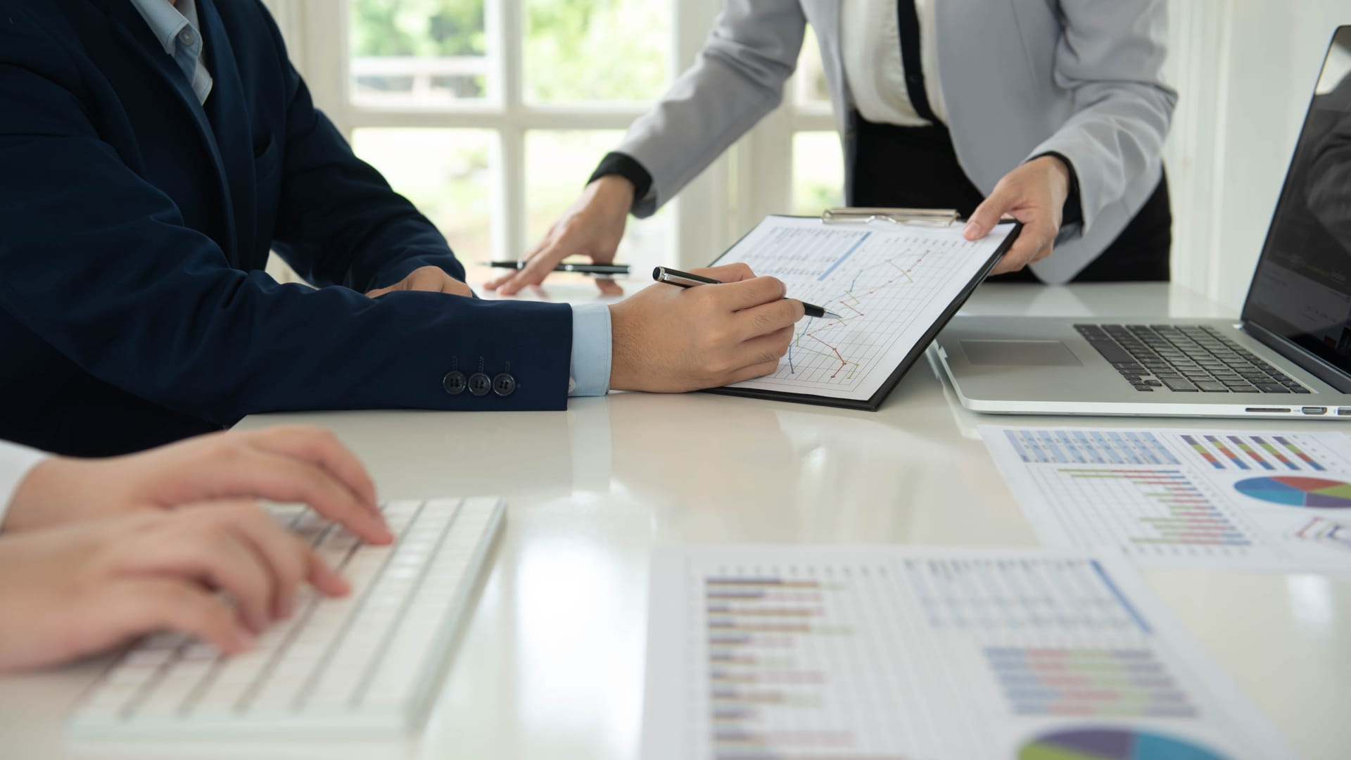 Meeting image with hands, keyboard, graphs and laptop