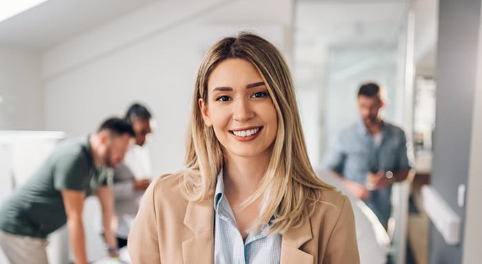 Young female office worker with colleagues around a table in background