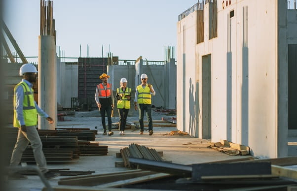 A group of people in hi-vis jackets and hats walking through a construction site