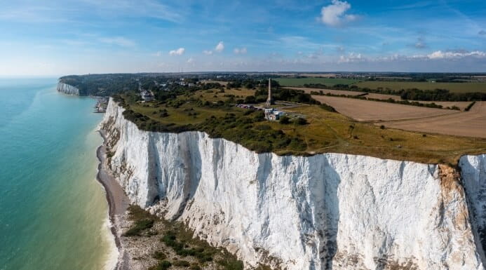 The iconic white chalk cliffs of the South East coastline with fields and countryside stretching inland