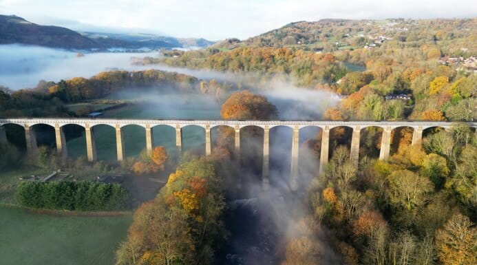 The Pontcysyllte Aqueduct stretching across a misty valley with autumn-colored trees in Wales