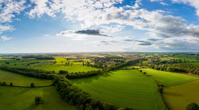 Expansive aerial view of green farmland and patchwork fields under a partly cloudy sky in Yorkshire and the Humber