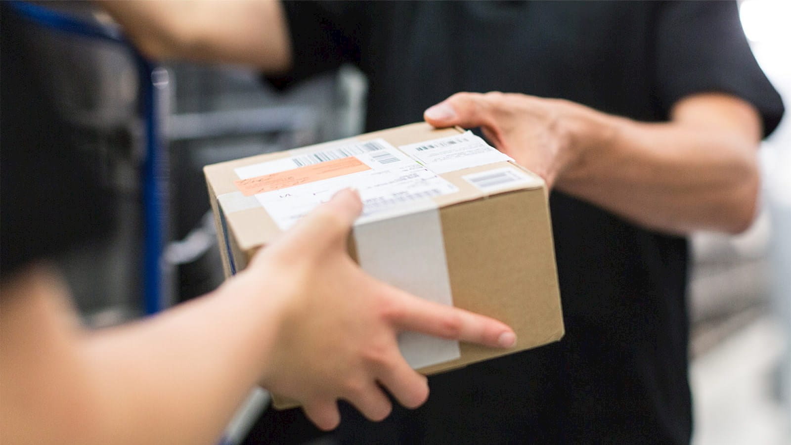 parcel box delivery passing between two people hands trade paperwork black shirts