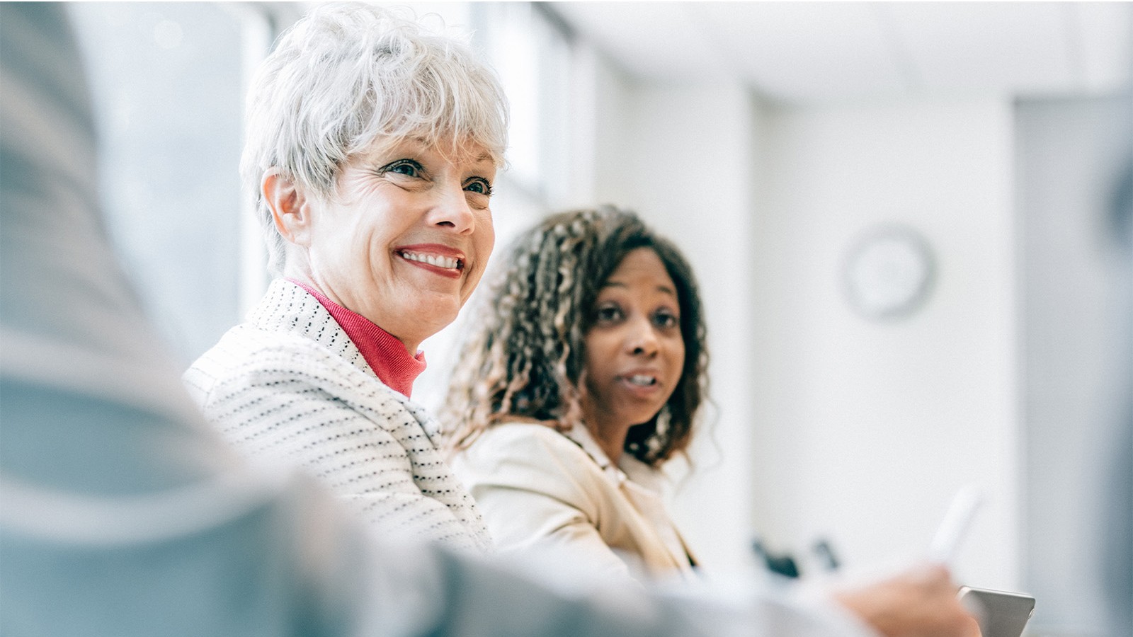 two women smiling colleagues employees financial directors board meeting white room