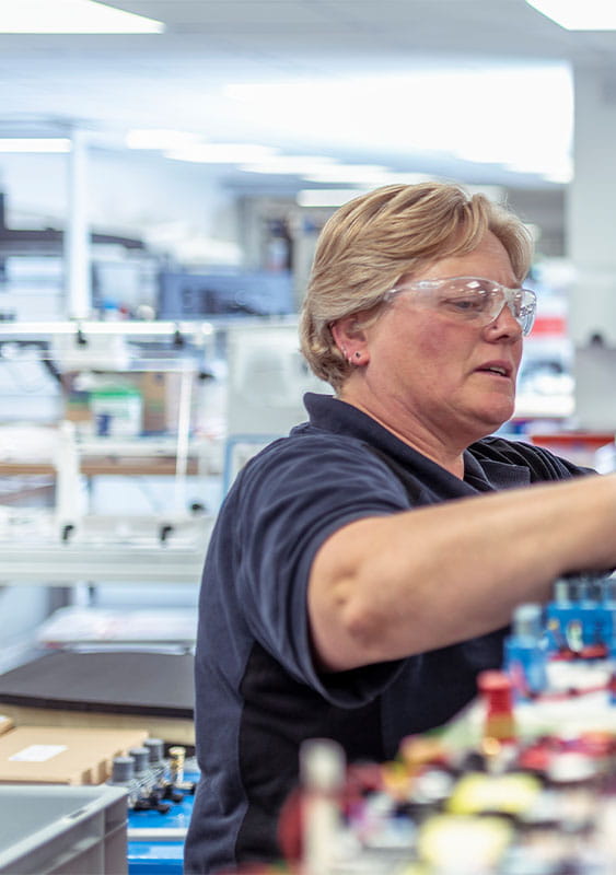 two employees man woman working in a lab pointing looking at computer parts