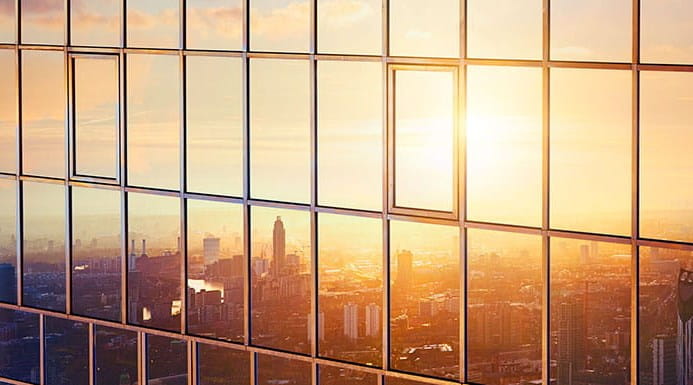 The reflection of a cityscape at sunset in the windows of a skyscraper