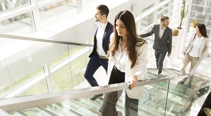 Three people in business attire walking up a staircase