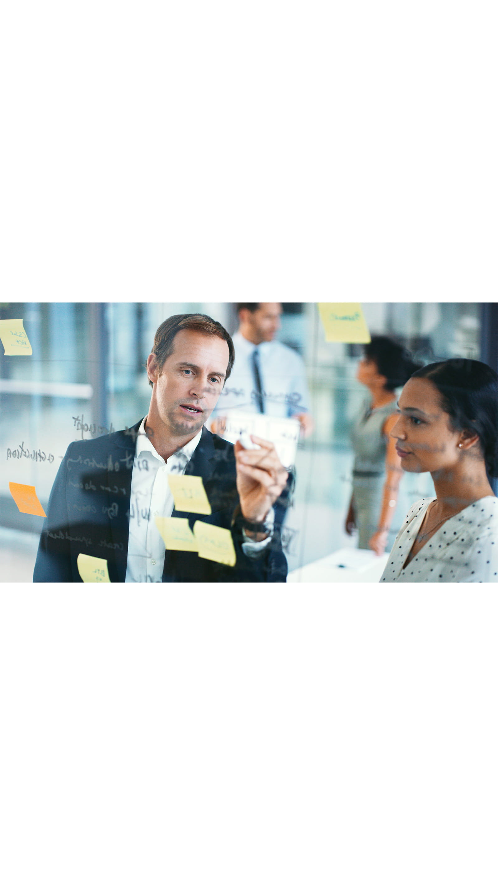 office meeting room man and woman colleagues brainstorming making notes on glass panel window yellow post-it notes