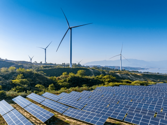 wind farm with solar panels green scenery and a blue sky