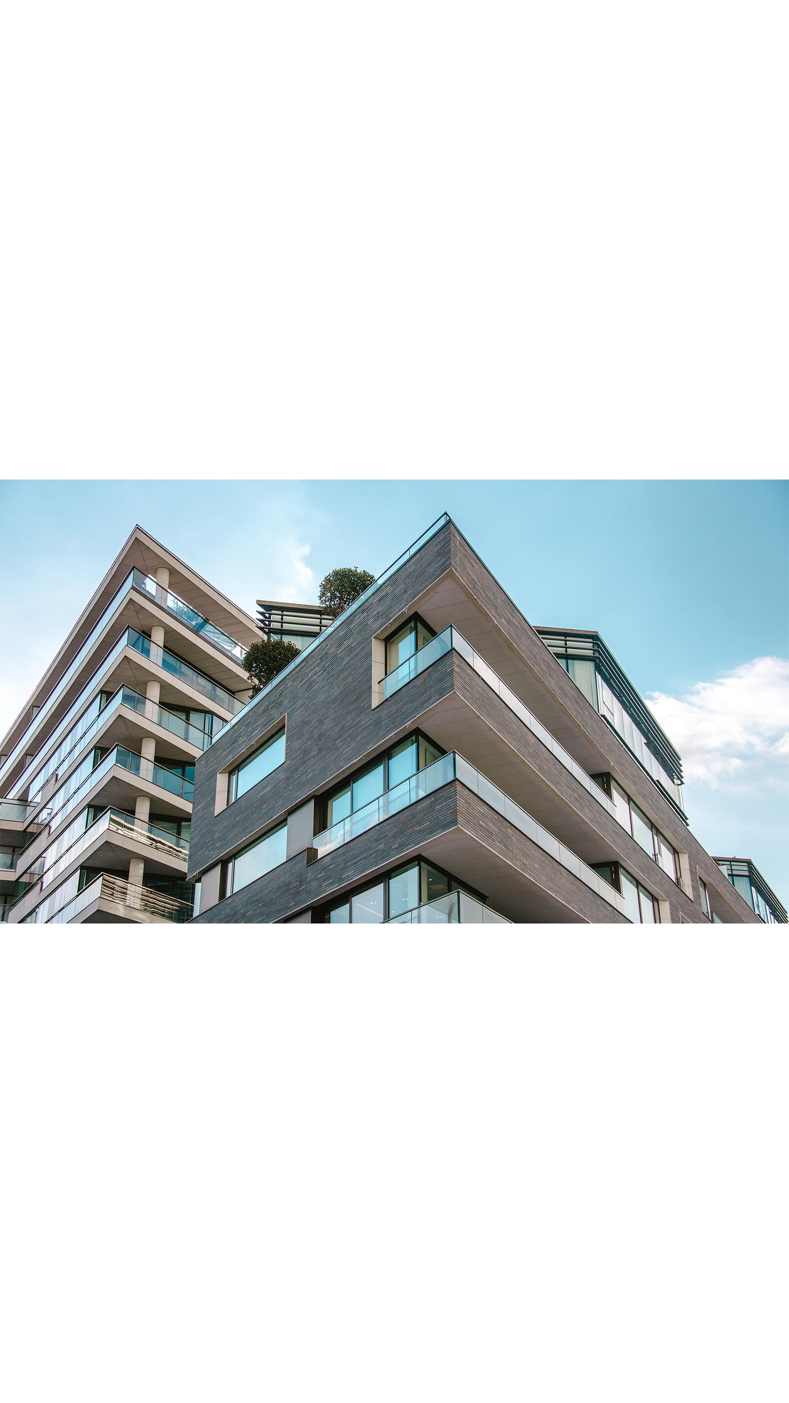 looking up at a modern apartment building flats tall skyscraper blue sky