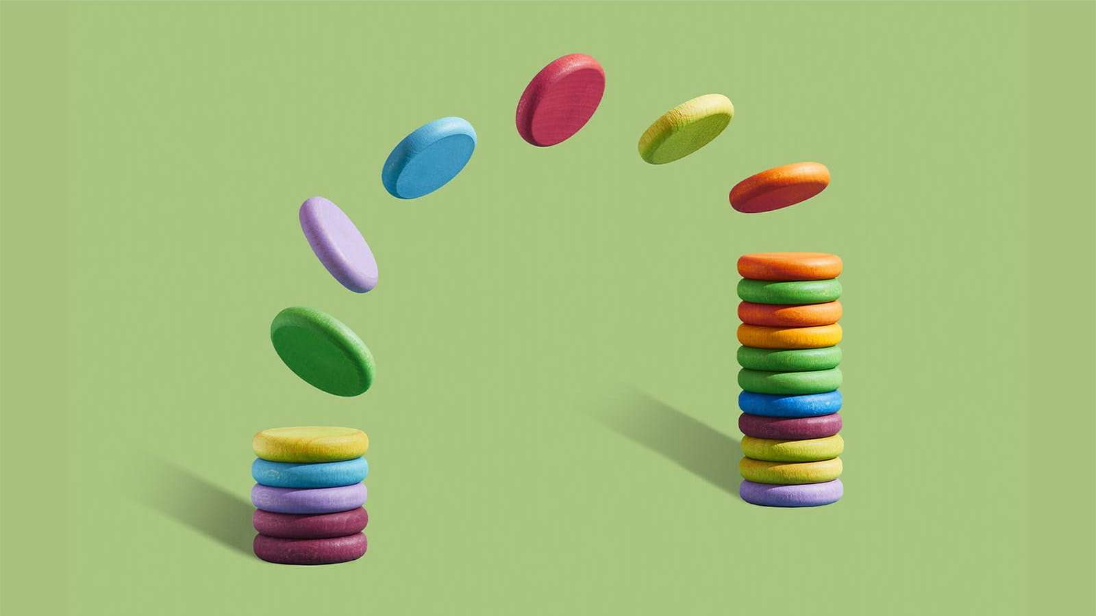 multicoloured plastic discs chips counters passing between two piles stacks green background