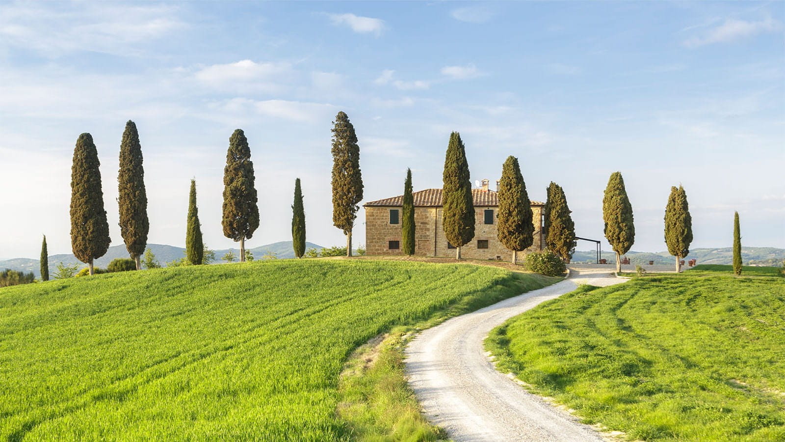 Italian villa house on top of hill green grass trees blue sky