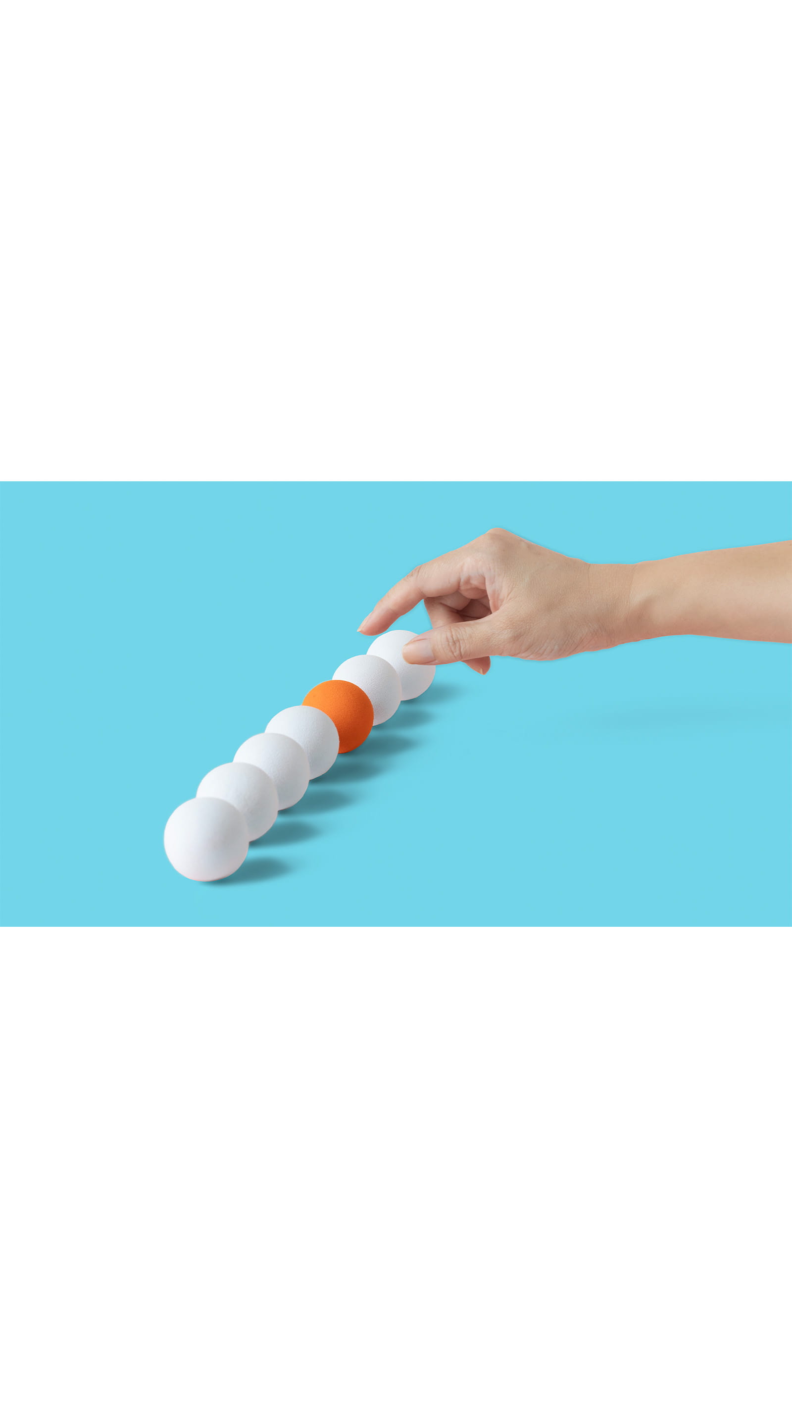 hand choosing picking up orange ping pong ball among a line of white ping pong balls, blue background