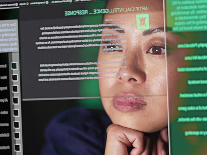 young asian woman looking at a transparent digital computer screen monitor showing green data