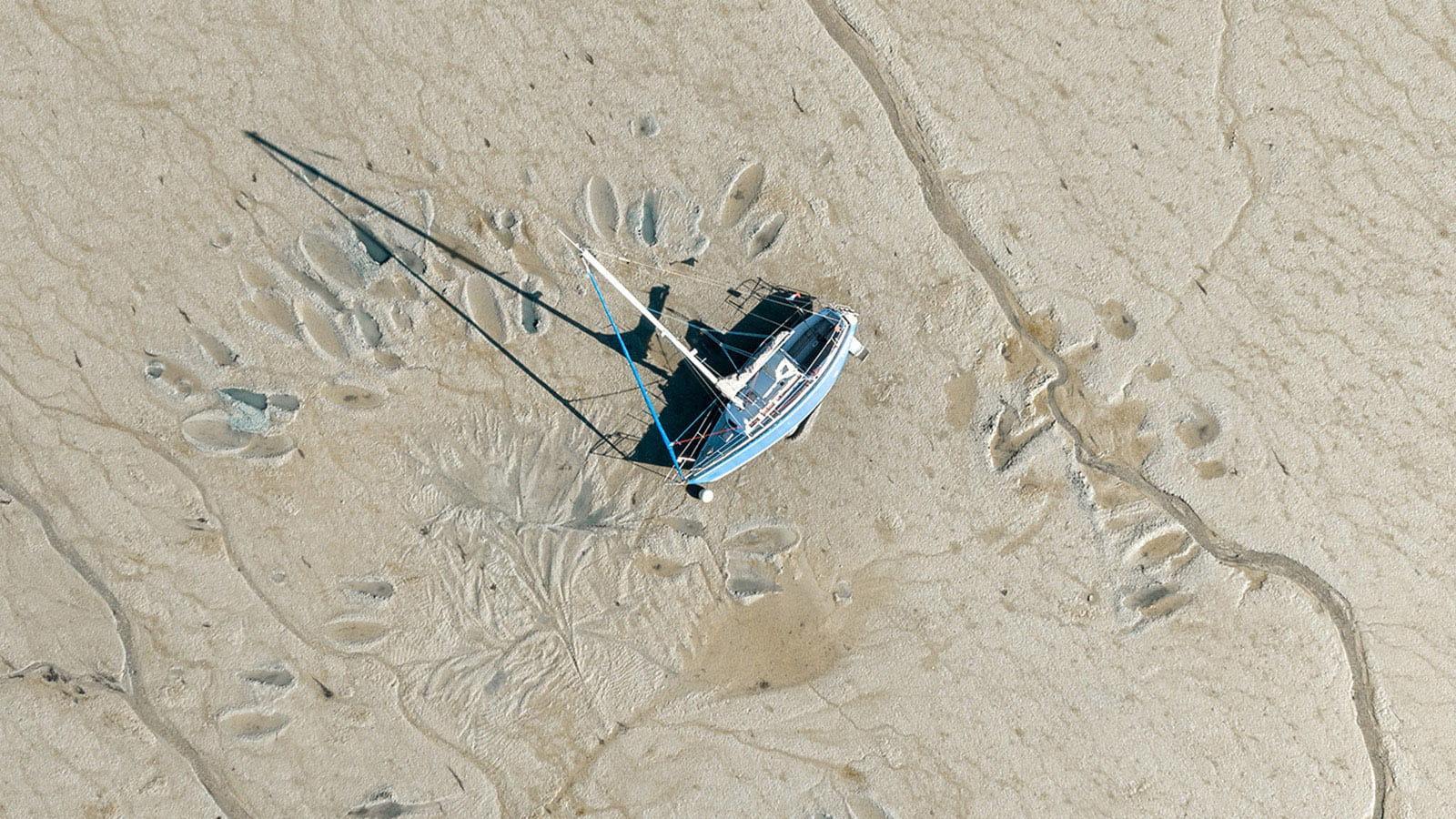 aerial birds eye view photo of a boat yacht stuck laying in mud tide out
