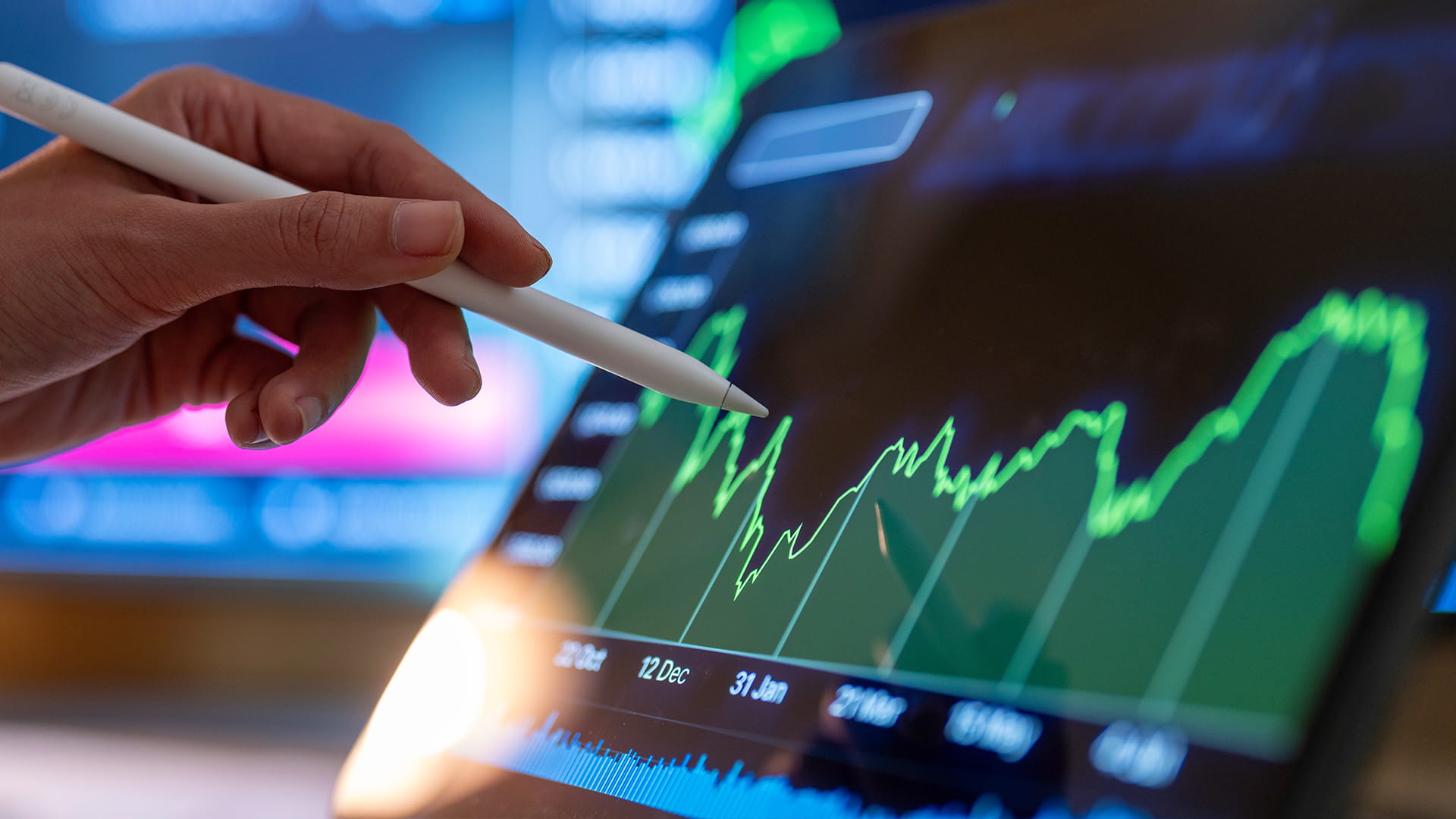 hand pointing a stylus pen at a tablet electronic screen showing a green line graph data