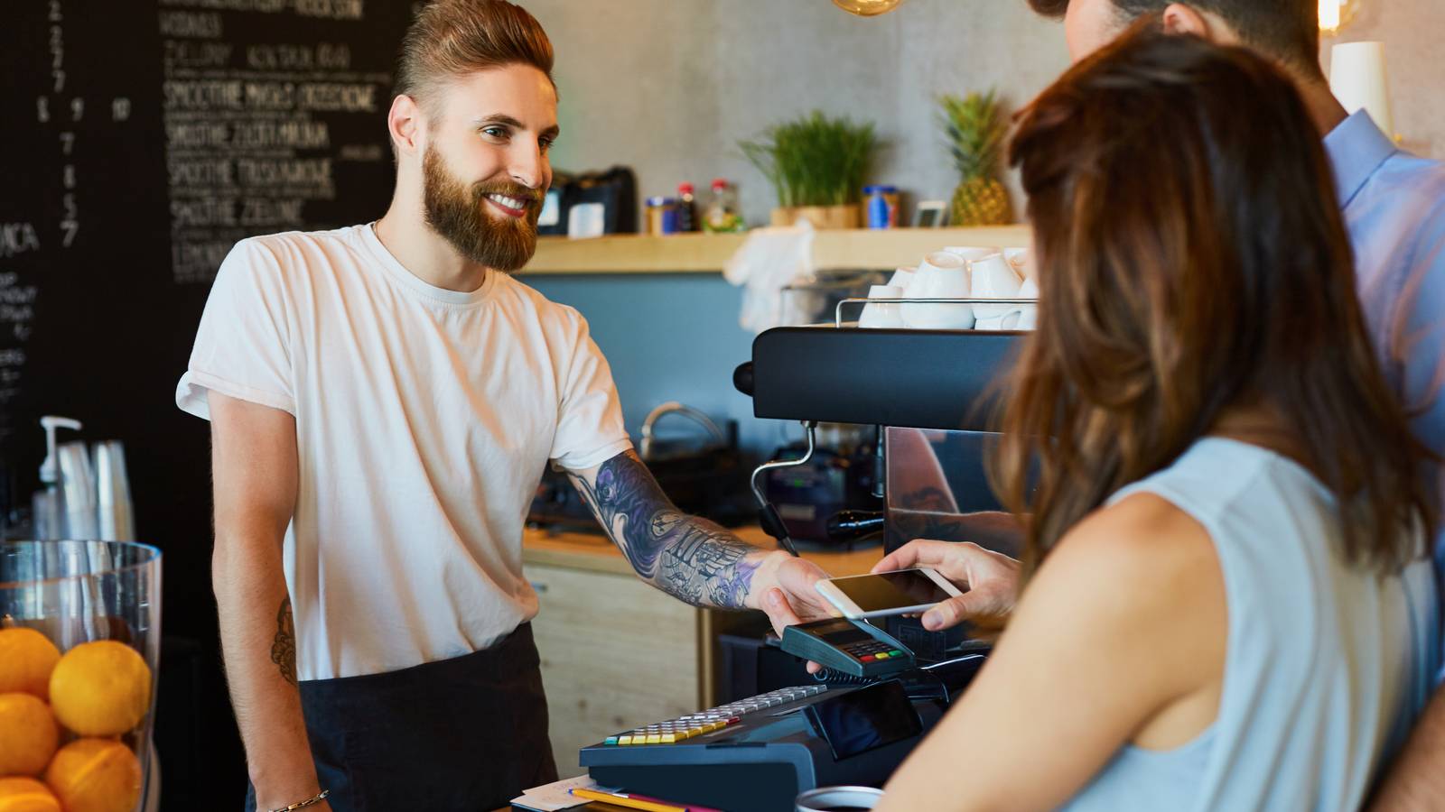 A male barista taking a mobile payment