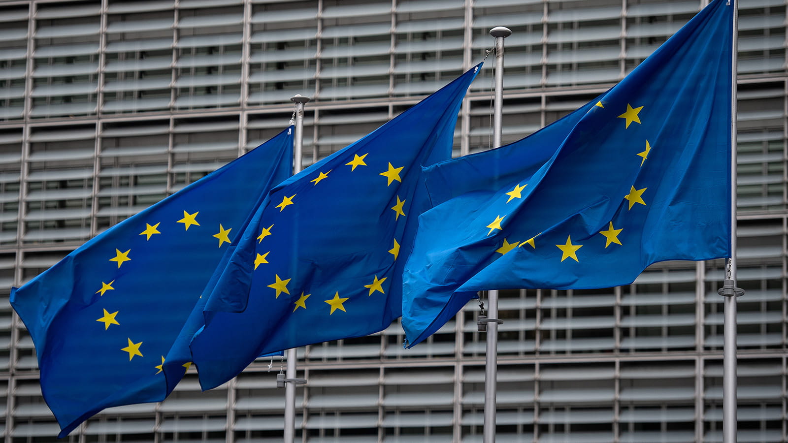 Three EU flags flying outside a building