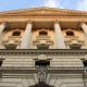 Looking up the front of the Bank of England towards a blue sky.