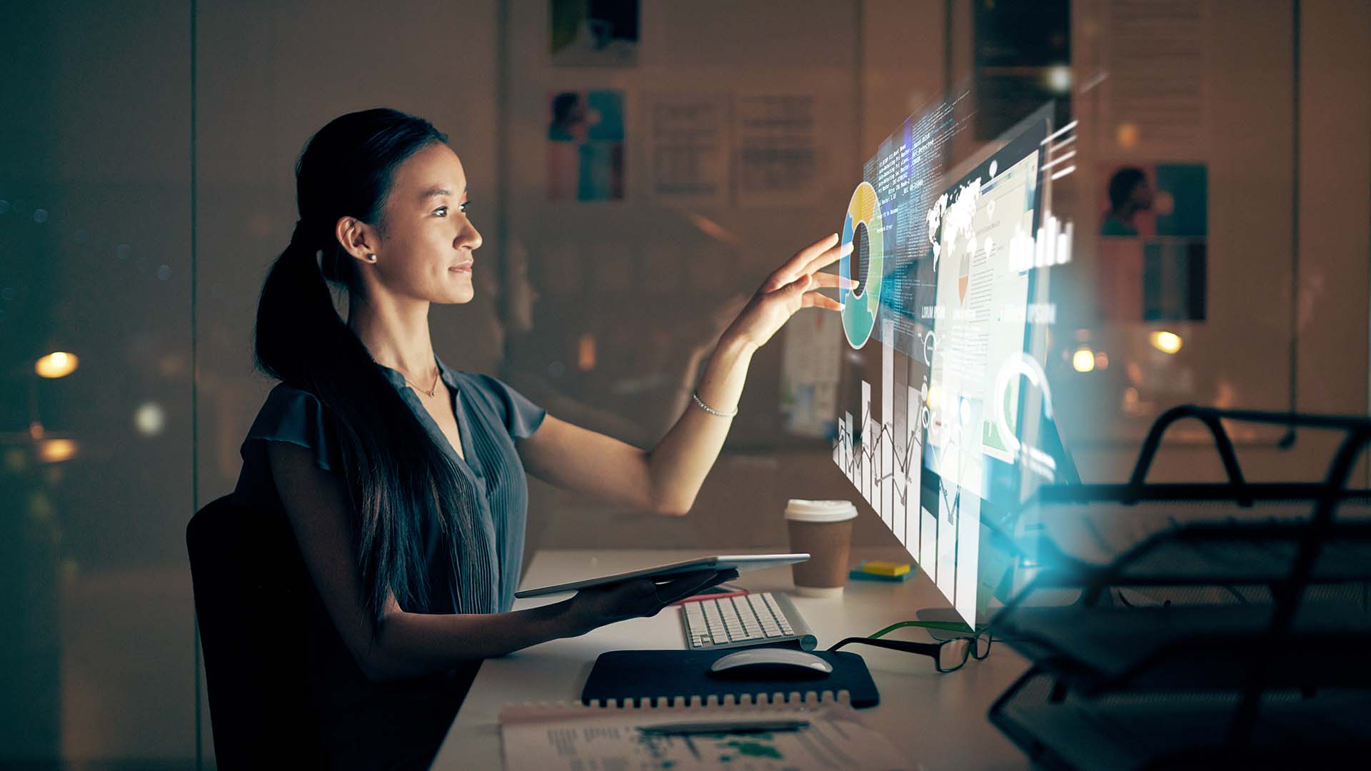 Shot of a young programmer using a digital tablet and computer at night in a modern office