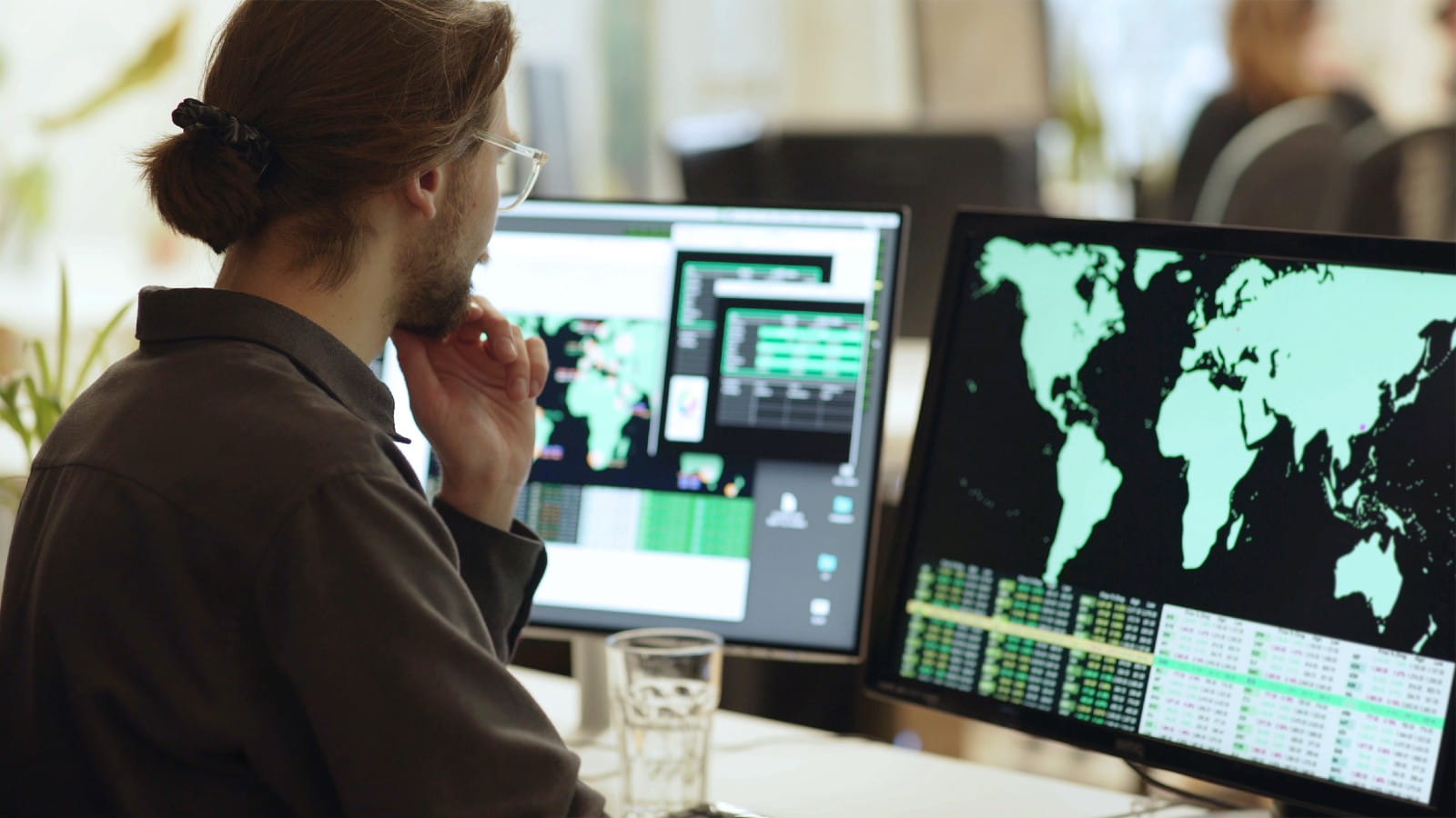 Person sitting in fron of screens with data on it. 