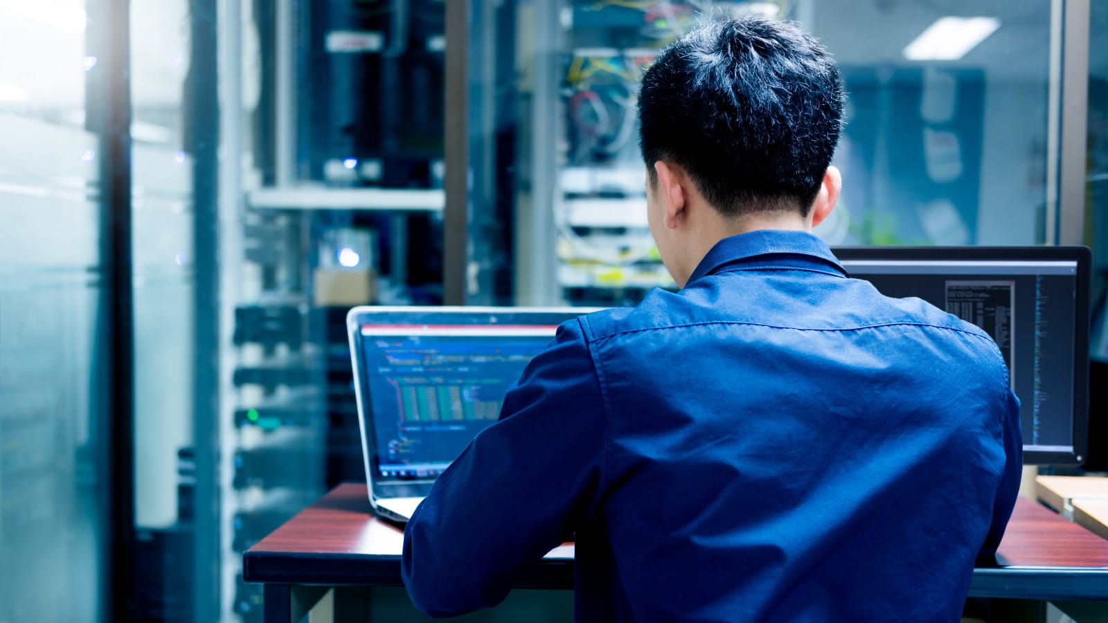Men at laptop with lots of data screens around him