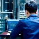 Men at laptop with lots of data screens around him