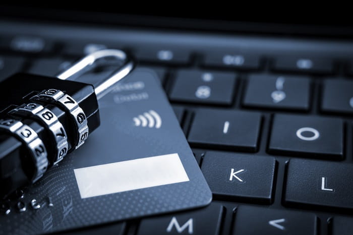 Close-up of a credit card and a combination padlock placed on a laptop keyboard, symbolizing online security and data protection.