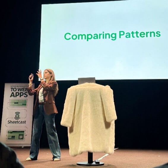 A woman on a stage in front of a power point on a big screen