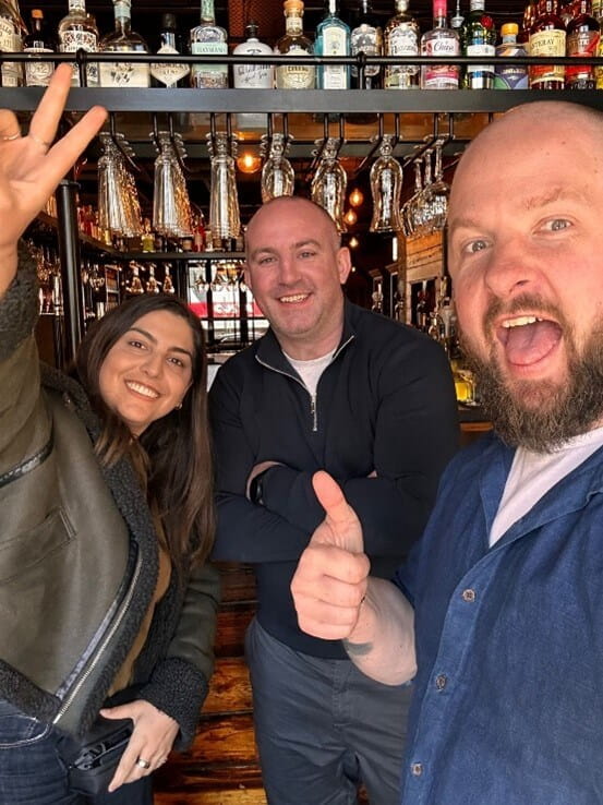 three people at a bar posing for the camera