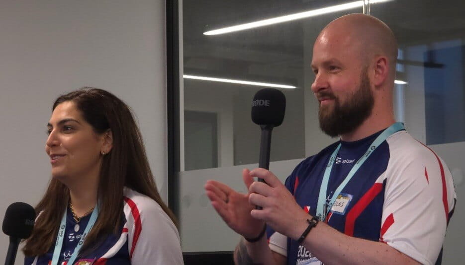 a man and a women wearing sports gear holding microphones